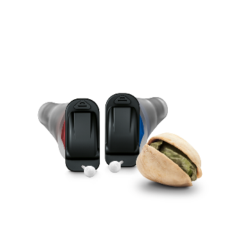 Silk Nx hearing aids next to a pistachio for size comparison