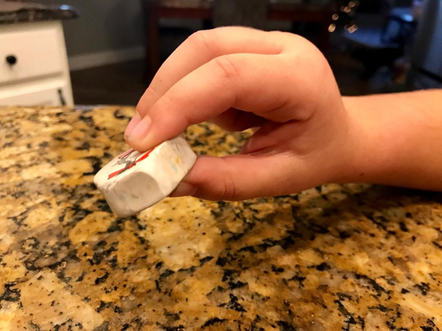 Pincer grasp demonstrated by a child hand holding a cat in the hat eraser