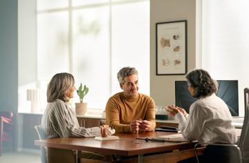 Consultation image of a couple at a deak with their hearing care professional