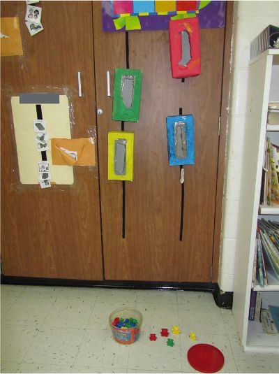 Colored tissue boxes velcroed vertically on a cabinet with container a container of small shapes on the floor