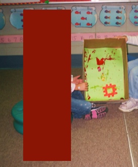Two children using a printer paper box to make artwork.