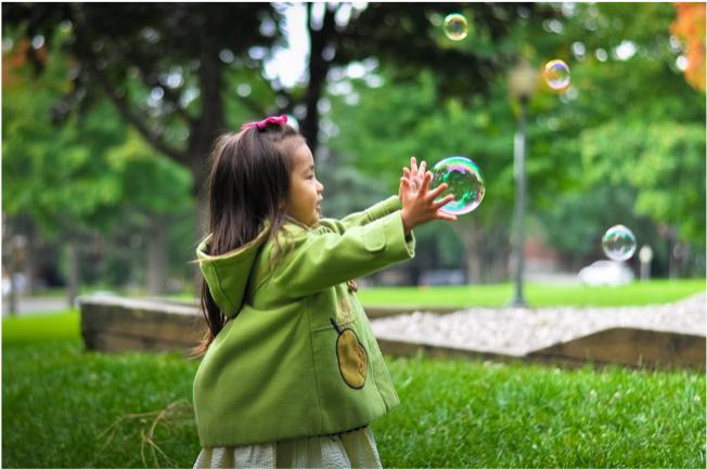 girl reaching for bubbles