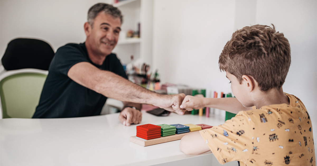 Therapist and young patient sitting at a table doing an exercise