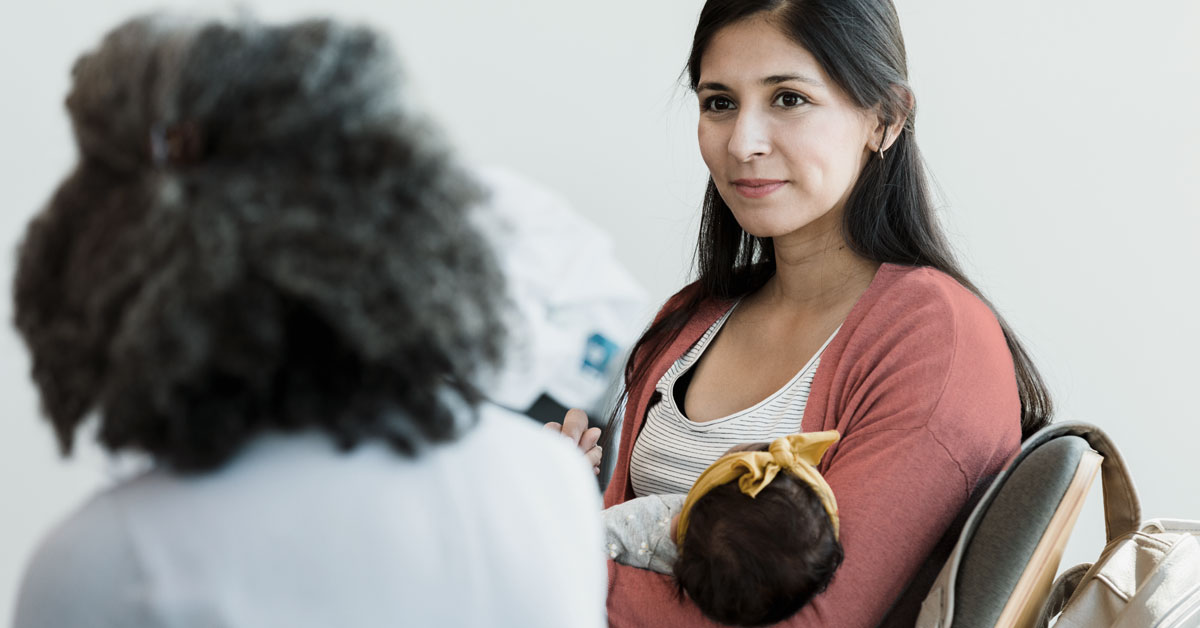 Two women talking while one holds a baby