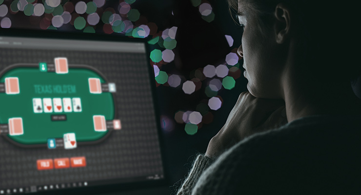 A person playing Texas Hold'em on a computer in a dark room