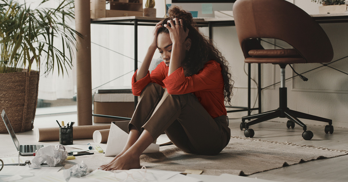 Woman sitting on the floor with her hands on her head and elbows on her knees
