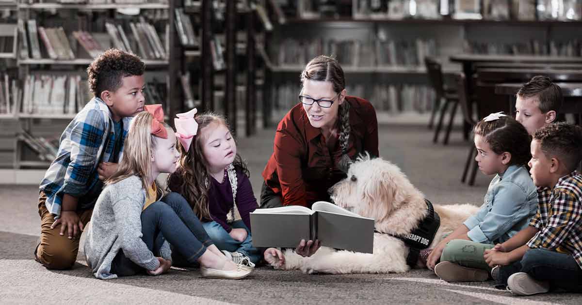 Group of children sitting with a therapist and a therapy dog