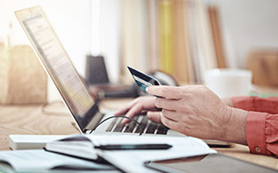 a closeup shot of hands holding a credit card over a laptop