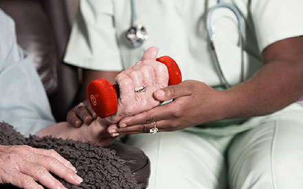 a patient is assisted in a home setting with a hand weight