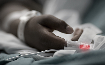 close up of a critical care patient's hand in hospital bed